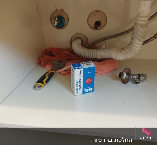 כלי עבודה וצינורות מתחת לכיור